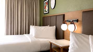 Una habitació d'hotel amb dos llits, una taula petita, una làmpada subjecta a la paret i un quadre amb marc.