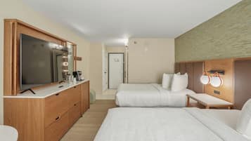 Habitación de hotel con una cama grande, un televisor, un aparador y una mesita de noche con lámparas.