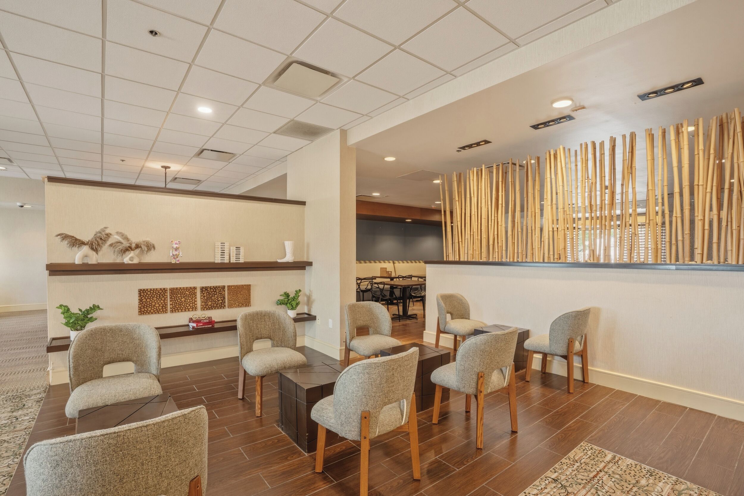 A modern hotel lobby with a reception desk, seating area, and a decorative bamboo wall.