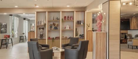 A modern interior with a reception desk, seating area, and a bookshelf with various decorative items.