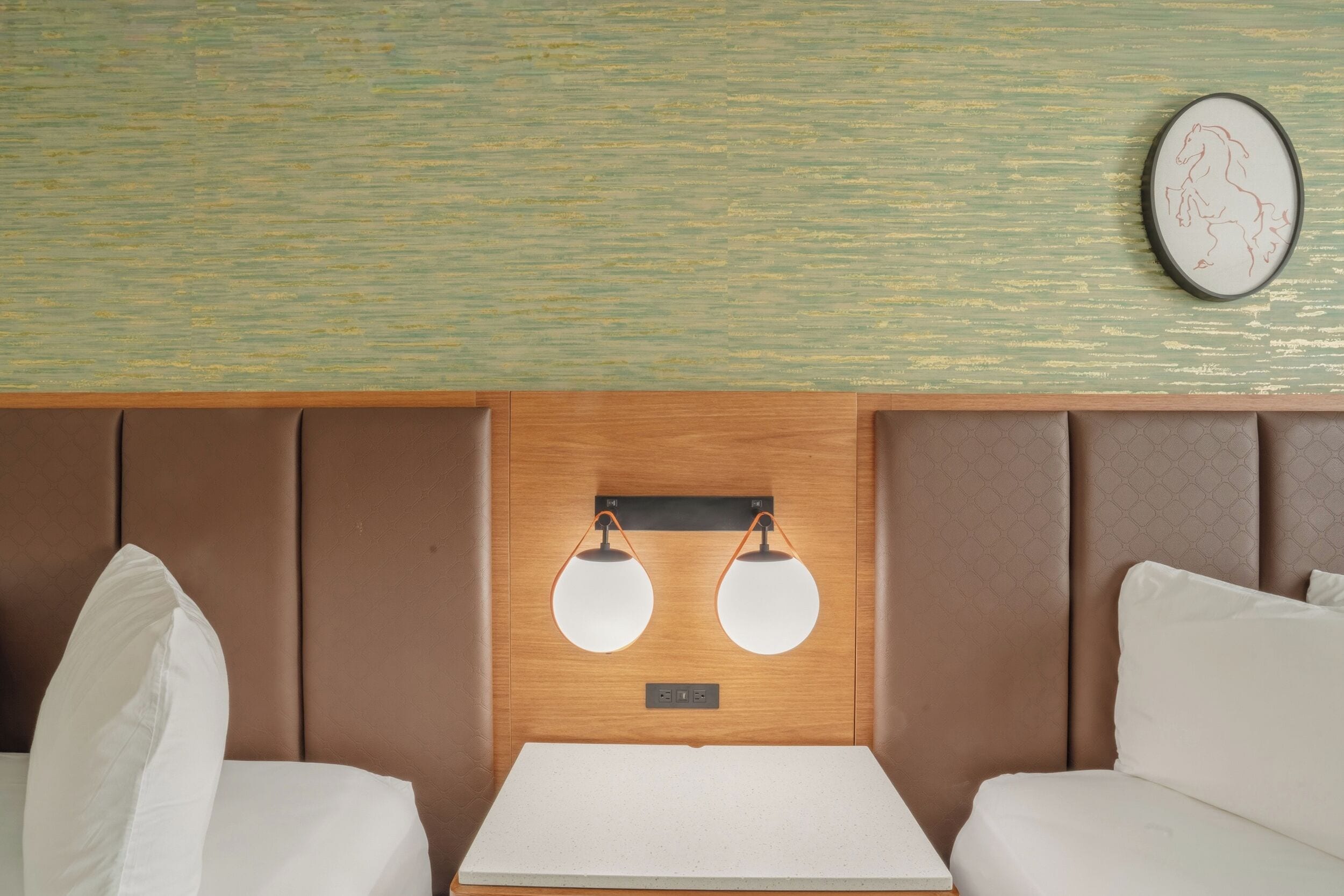A room with a wooden headboard, two bedside tables, white bedding, and a wall-mounted light fixture.