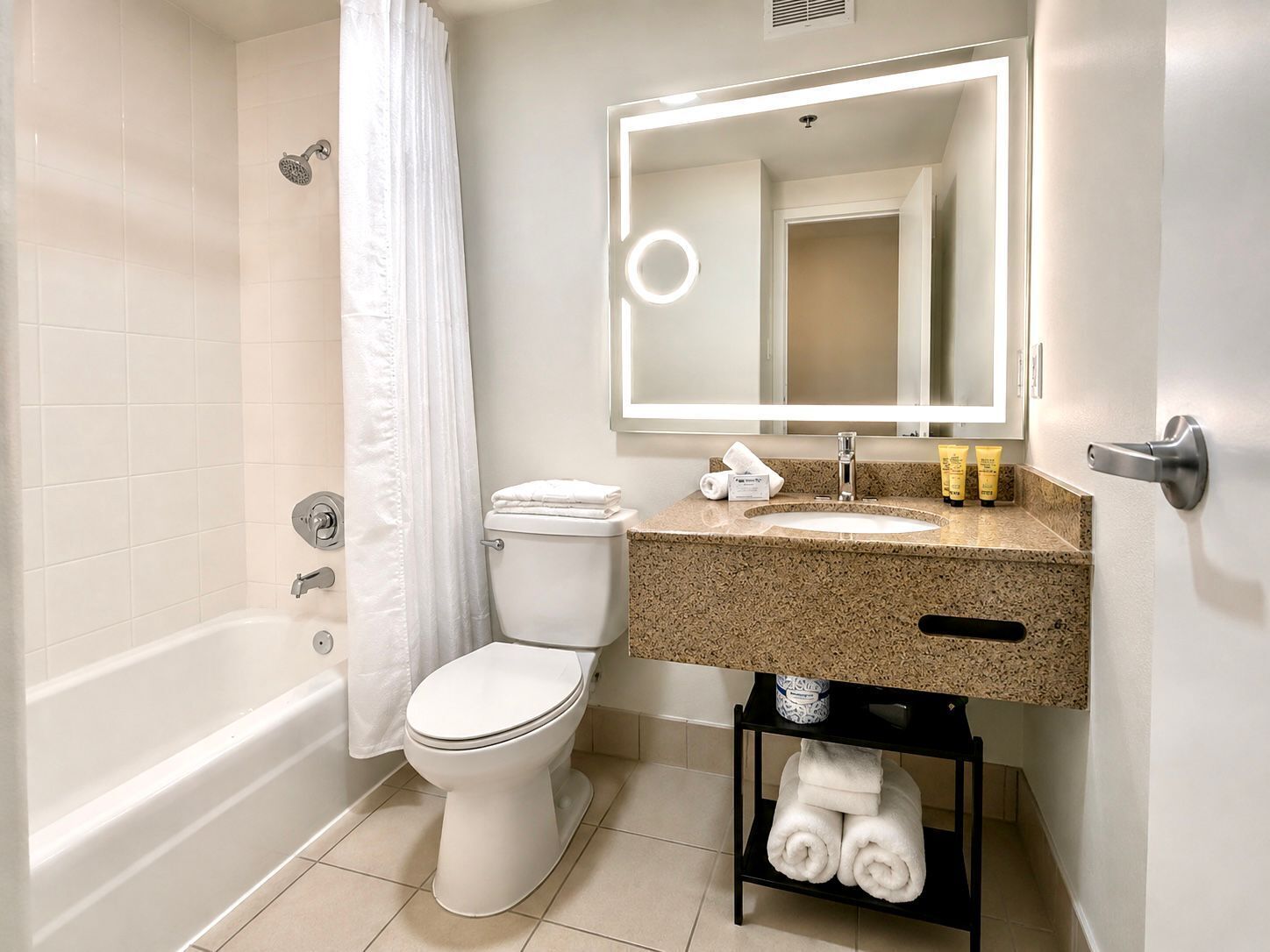 A bathroom with a bathtub, toilet, sink, and a mirror above the sink.