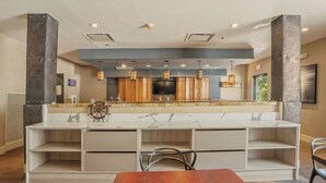 A modern kitchen with a central island, built-in appliances, and pendant lighting. - Kozy Hotel Dallas DFW Airport Area West (Bedford)