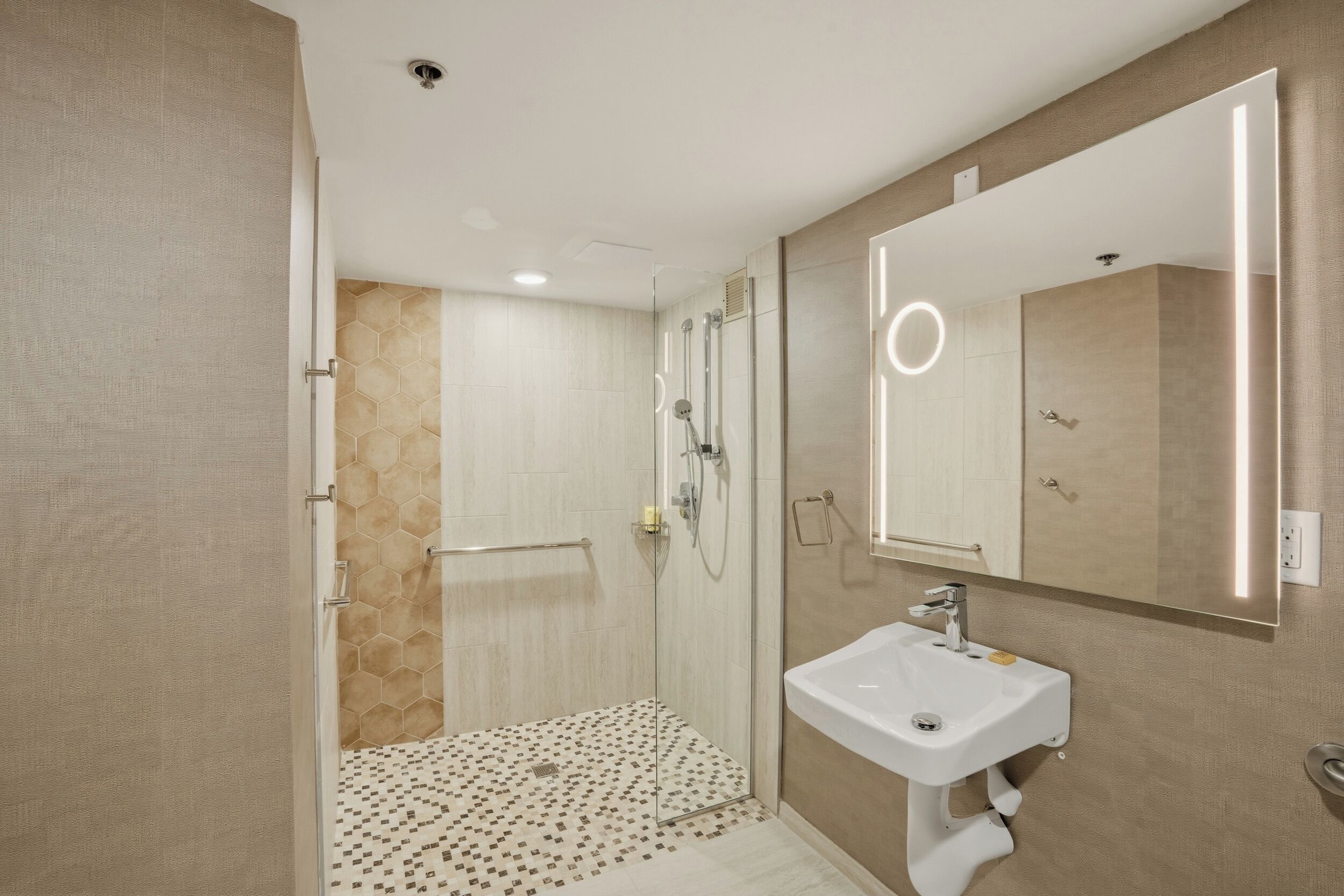 A modern bathroom with a glass-enclosed shower, a white sink, and a large mirror.