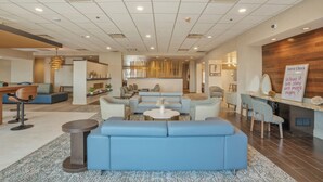 A modern hotel lobby with a seating area, a reception desk, and a 'Guest Check' sign. - Kozy Hotel Dallas DFW Airport Area West (Bedford)