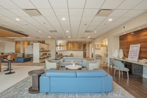 A modern hotel lobby with a seating area, a reception desk, and a 'Guest Check' sign.