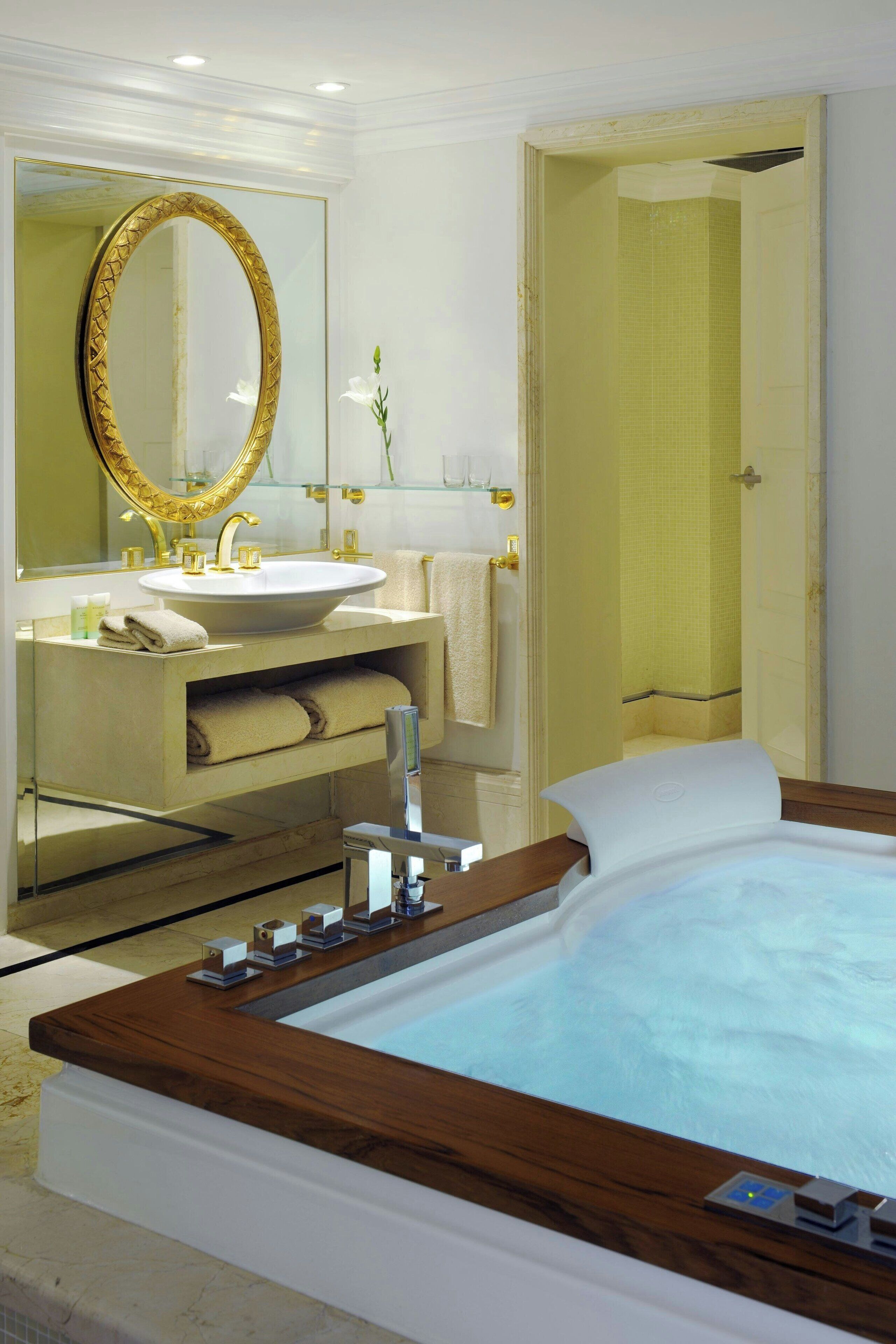A modern bathroom with a large oval mirror, a freestanding bathtub, a vanity with a sink, and a shower area.