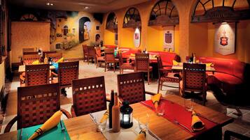 A restaurant with wooden tables and chairs, red cushioned seating, and a mural of a street scene on the walls.