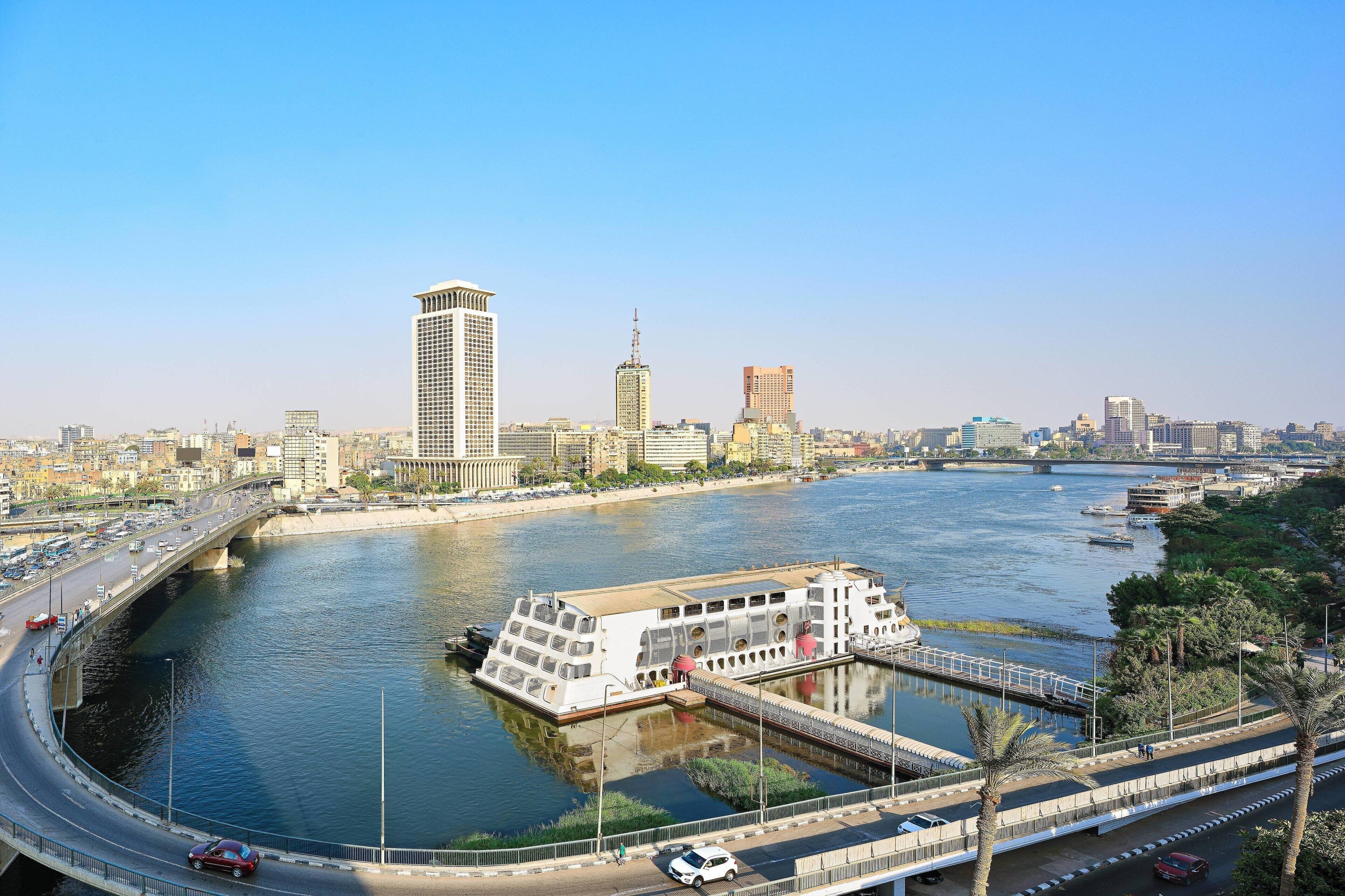 A river with a bridge and a building with a unique design near the water.
