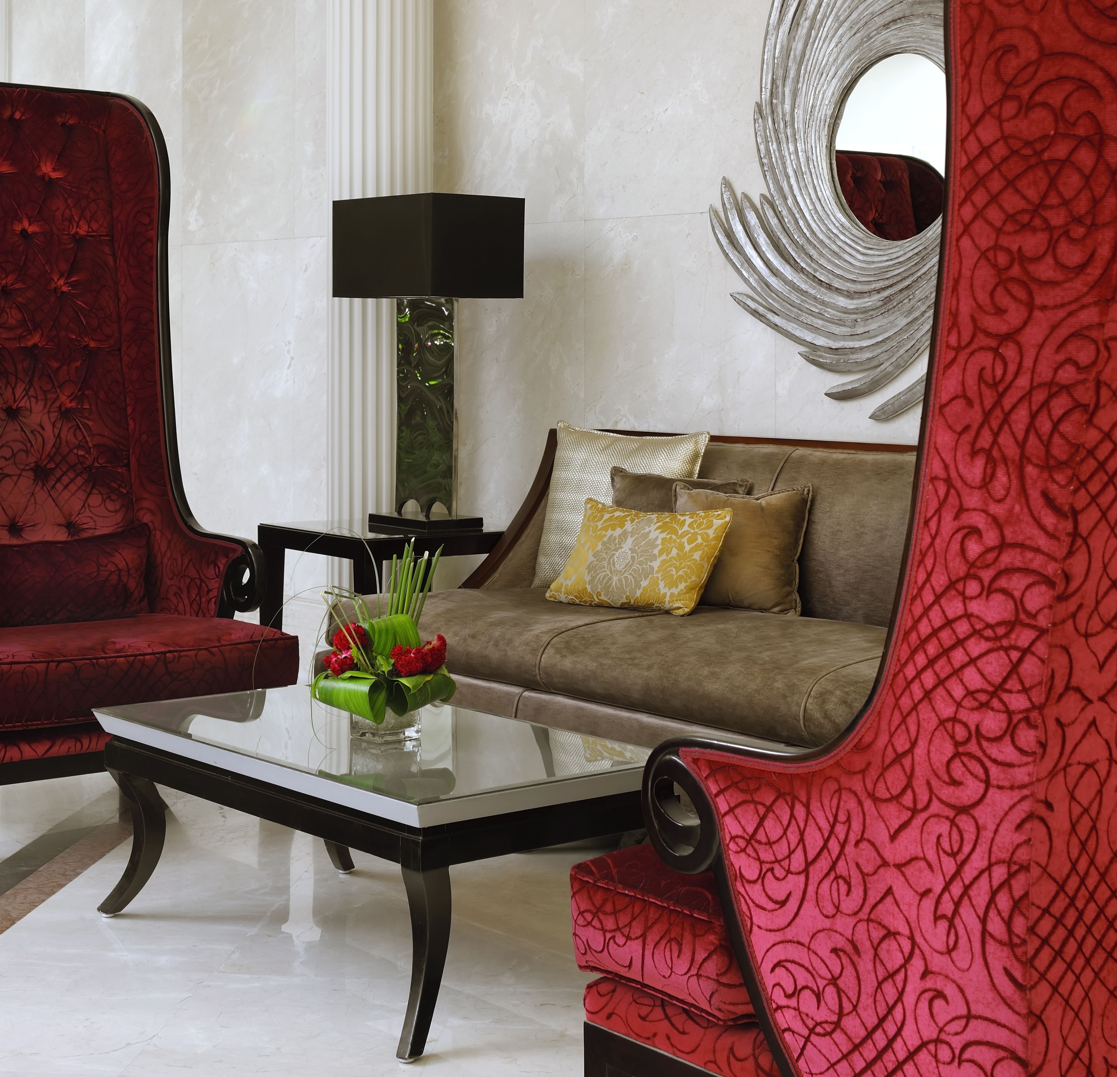 Una sala de estar moderna con un sillón rojo, un sofá marrón y una mesa de centro de vidrio.