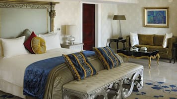 A luxurious bedroom with a large bed, a chaise lounge, a sofa, and a painting on the wall.