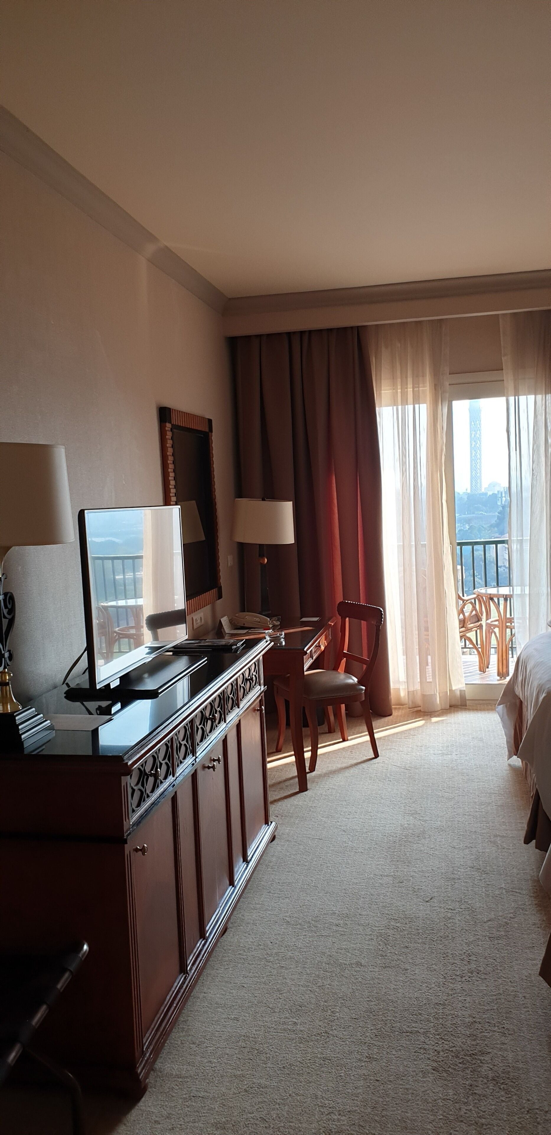 Une chambre d’hôtel équipée d’un bureau, d’une chaise, d’un lit et offrant une vue sur une tour par la fenêtre.