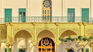 A building with ornate arches and a balcony with green railings.