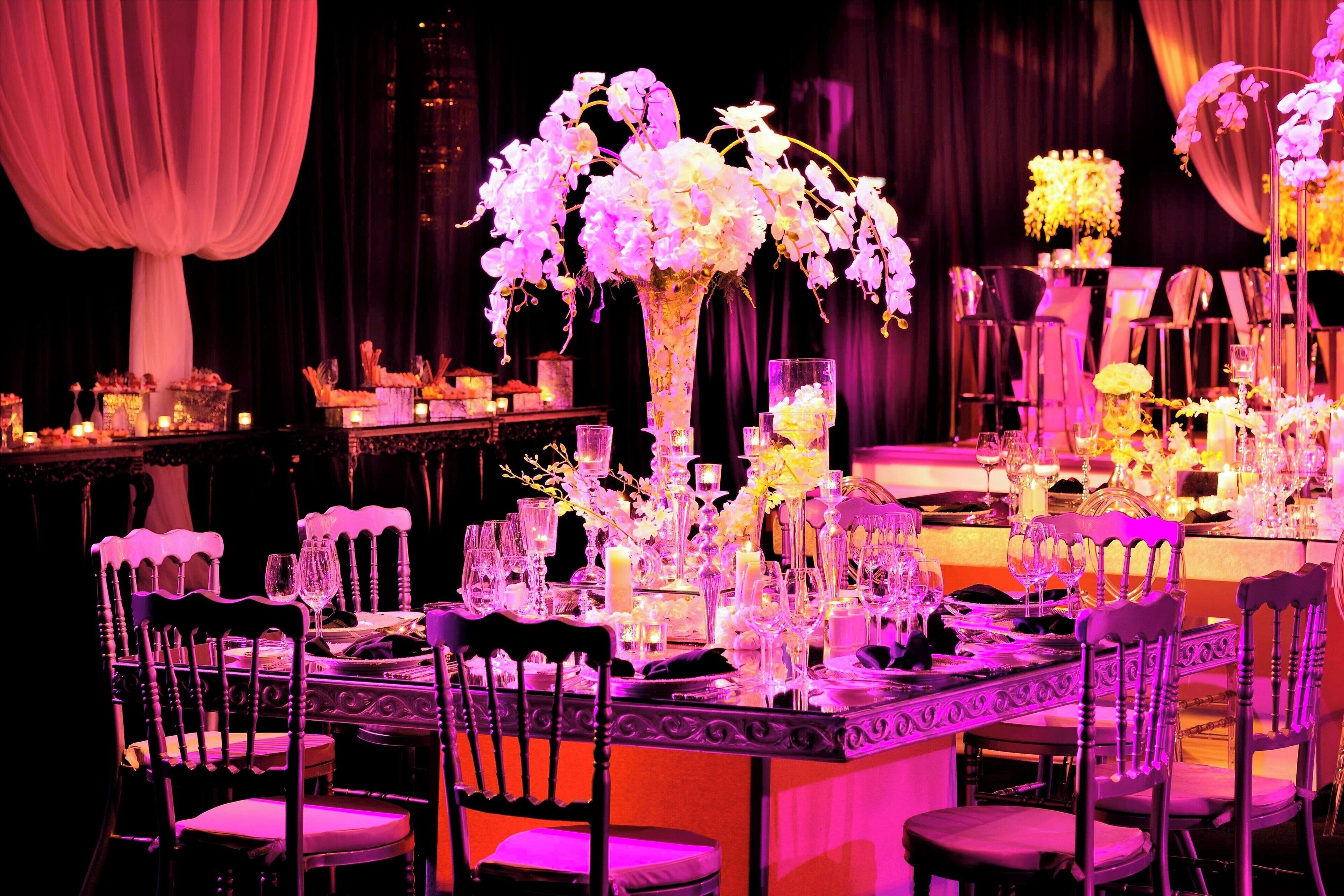A formal dining table set with chairs, floral centerpieces, and candles.