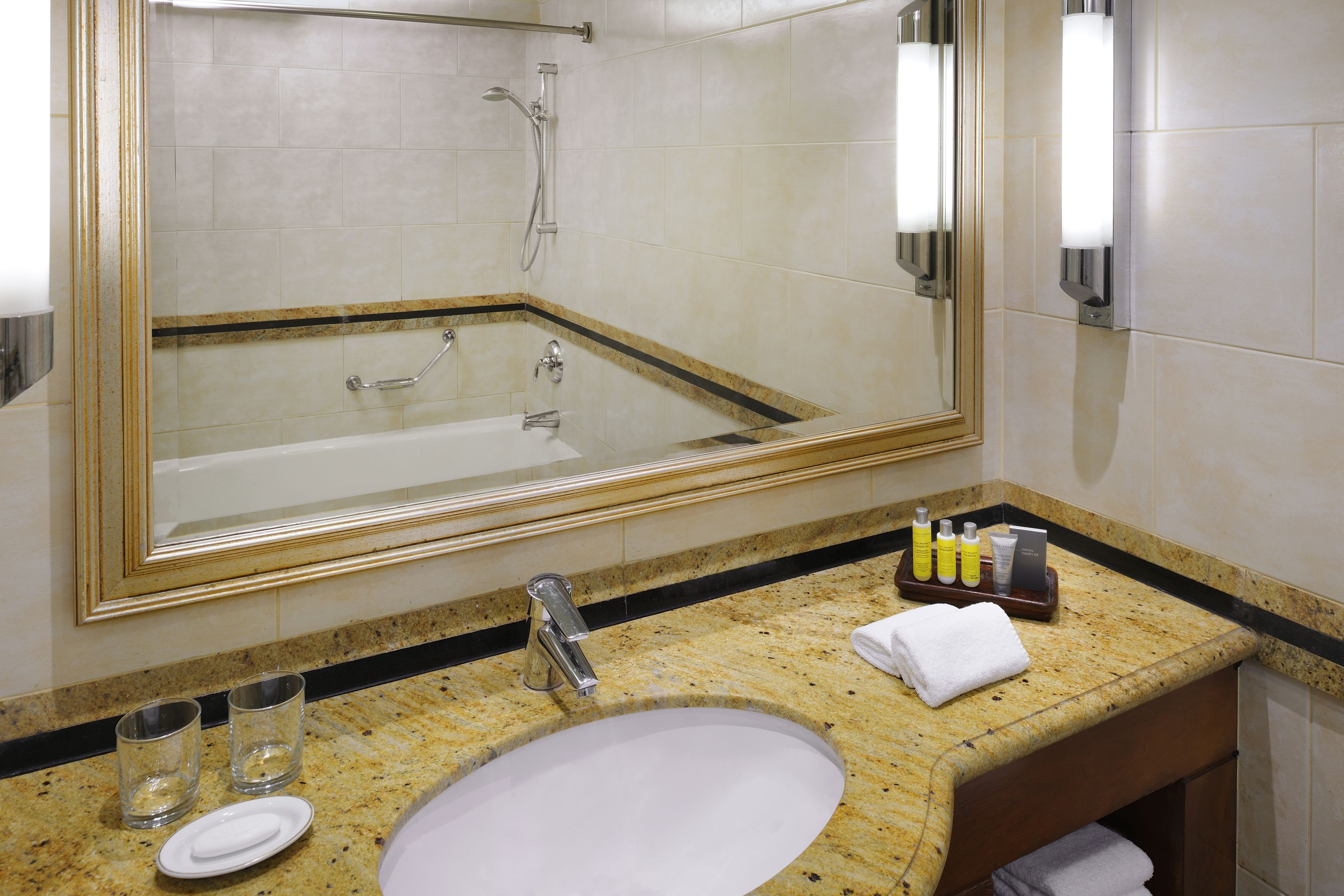 A bathroom with a large mirror, a sink, and a shower.