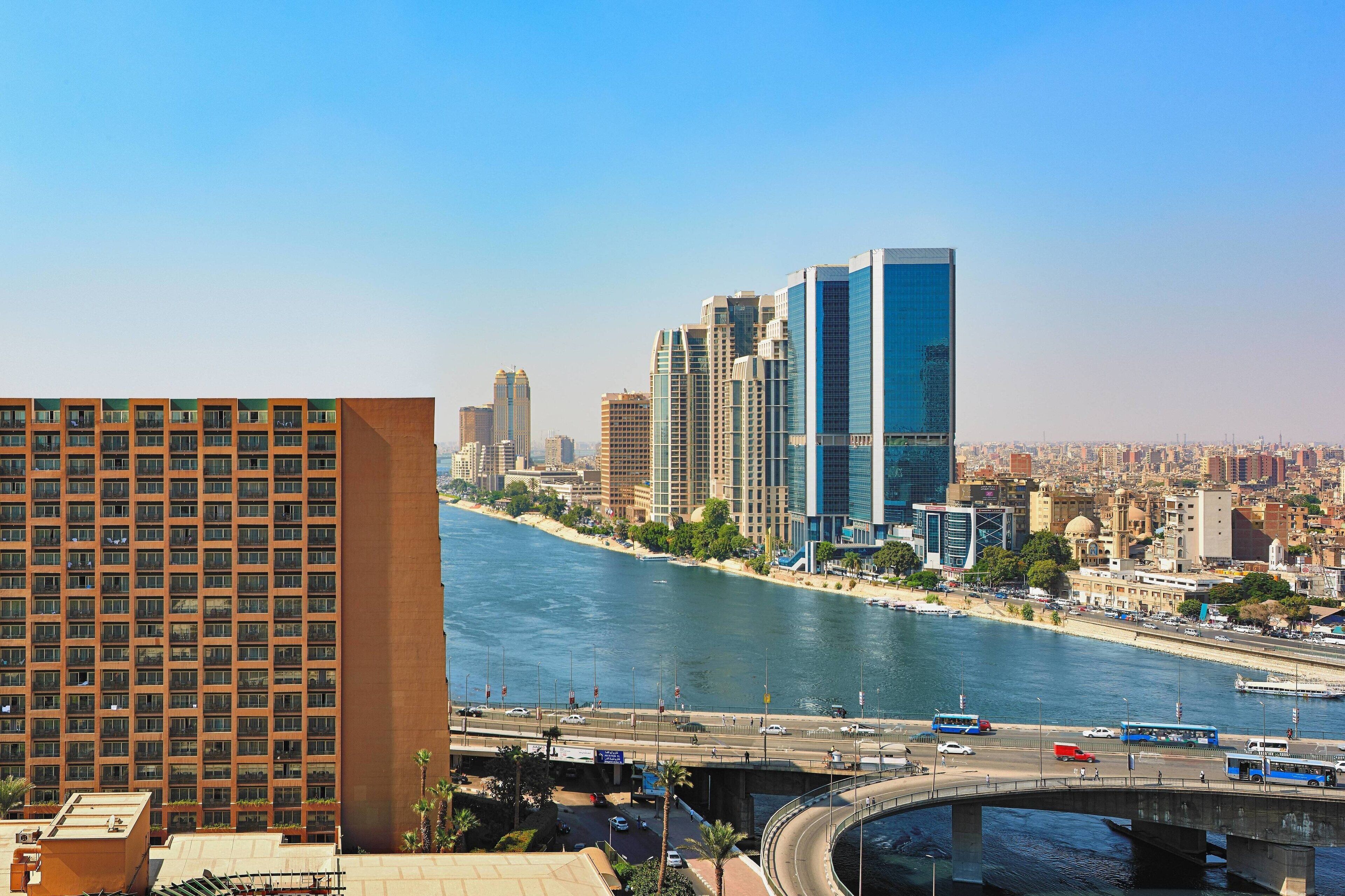 A river with a bridge, high-rise buildings, and a modern hotel with a view of the river.