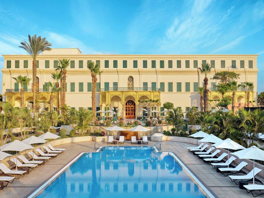 Una piscina al aire libre, sombrillas, sillones reclinables de piscina