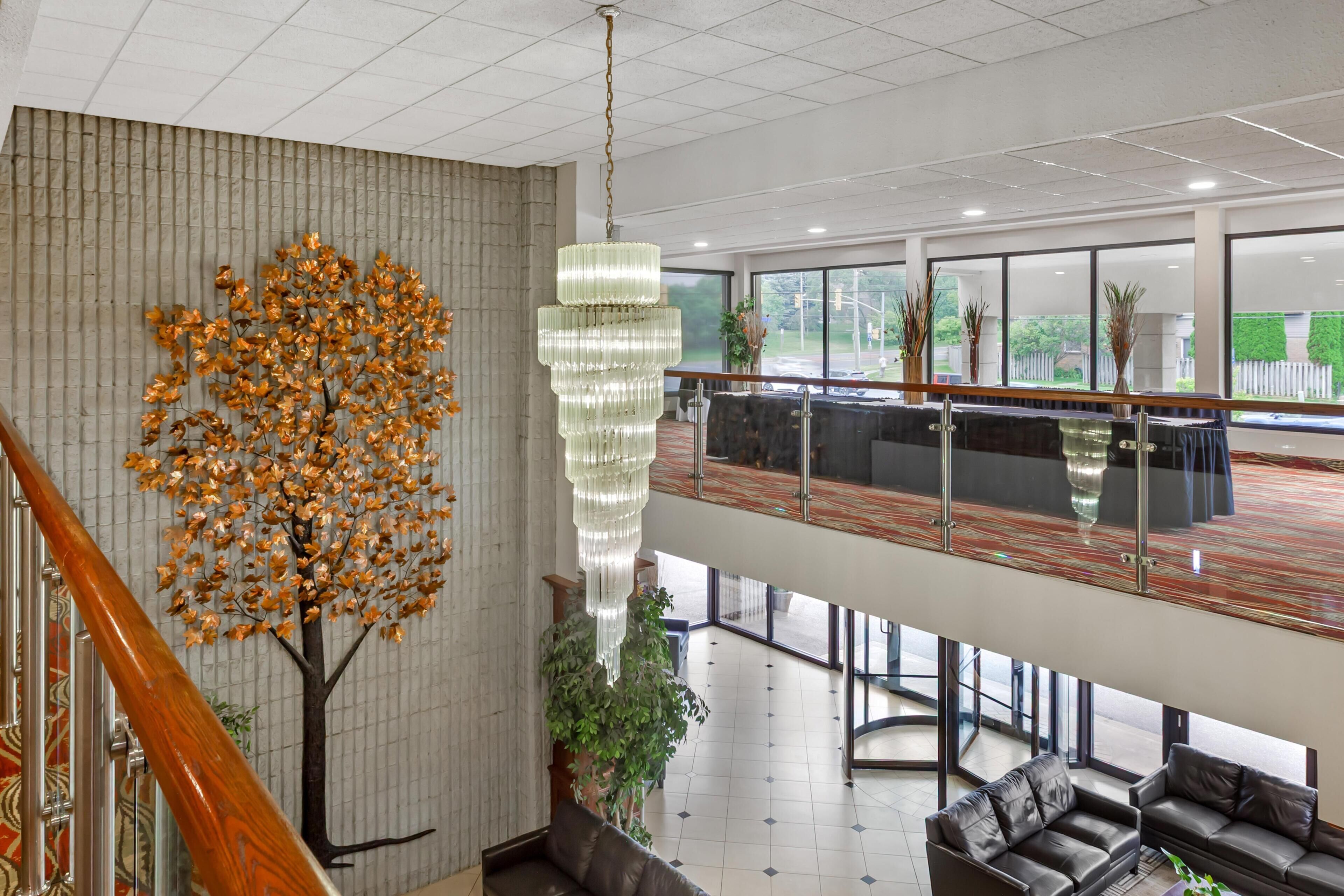 A modern lobby with a staircase, a chandelier, a reception desk, and a view of the outdoors.