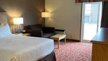 A hotel room with a large bed, a desk, a chair, a sofa, and two lamps.