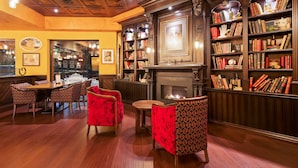A library with bookshelves, a fireplace, and red upholstered chairs. - Best Western Plus Cobourg Inn & Convention Centre (Cobourg)