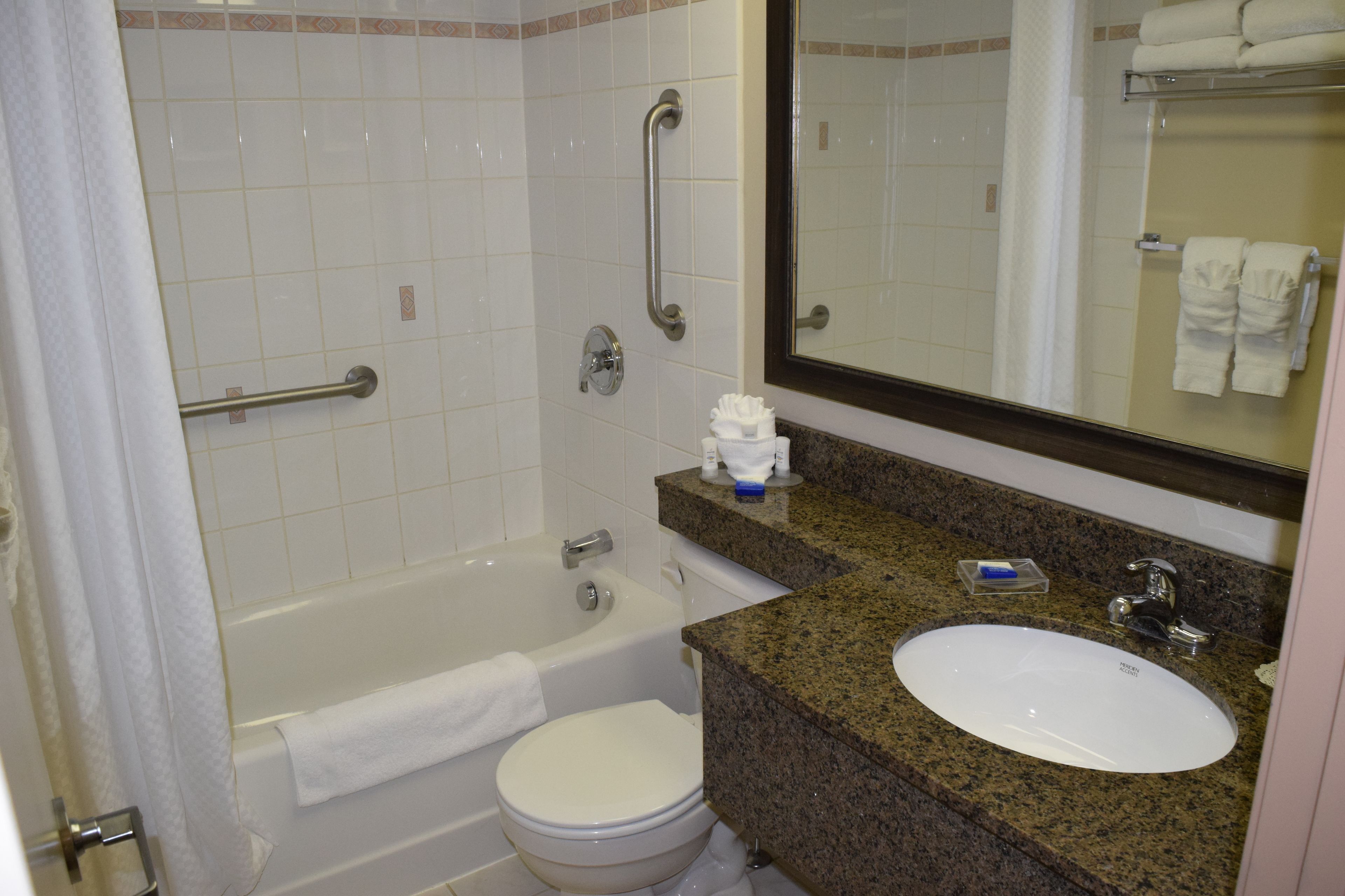 A bathroom with a bathtub, toilet, sink, and a mirror.