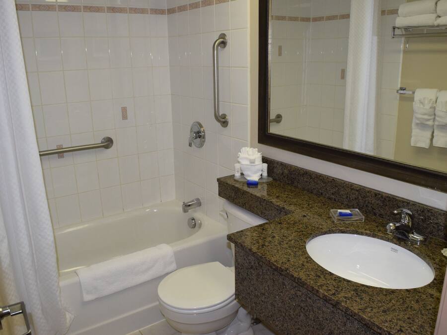 A bathroom with a bathtub, toilet, sink, and a mirror.