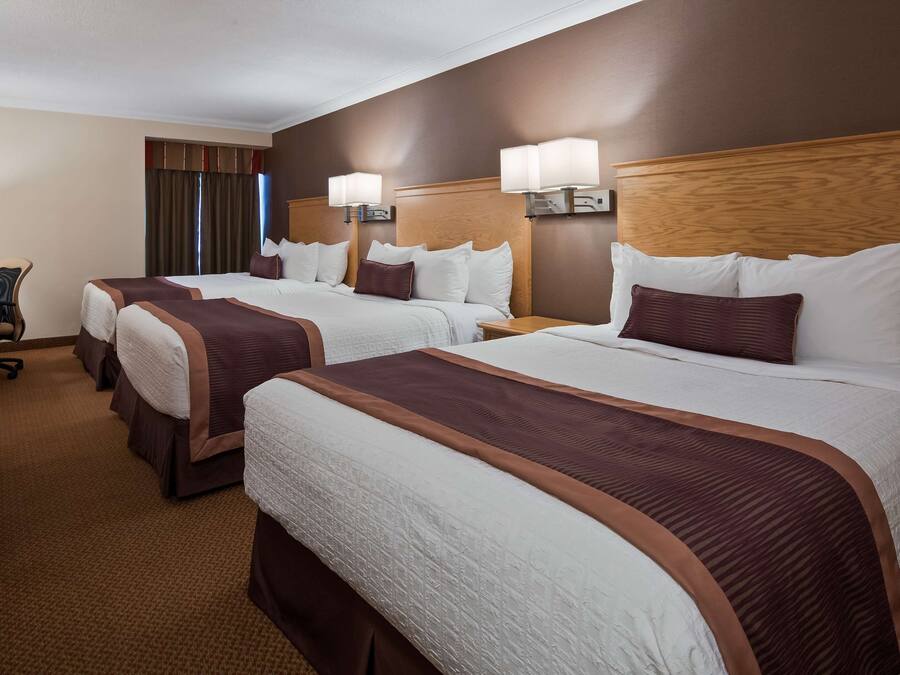 A hotel room with three beds, a desk, and a chair.