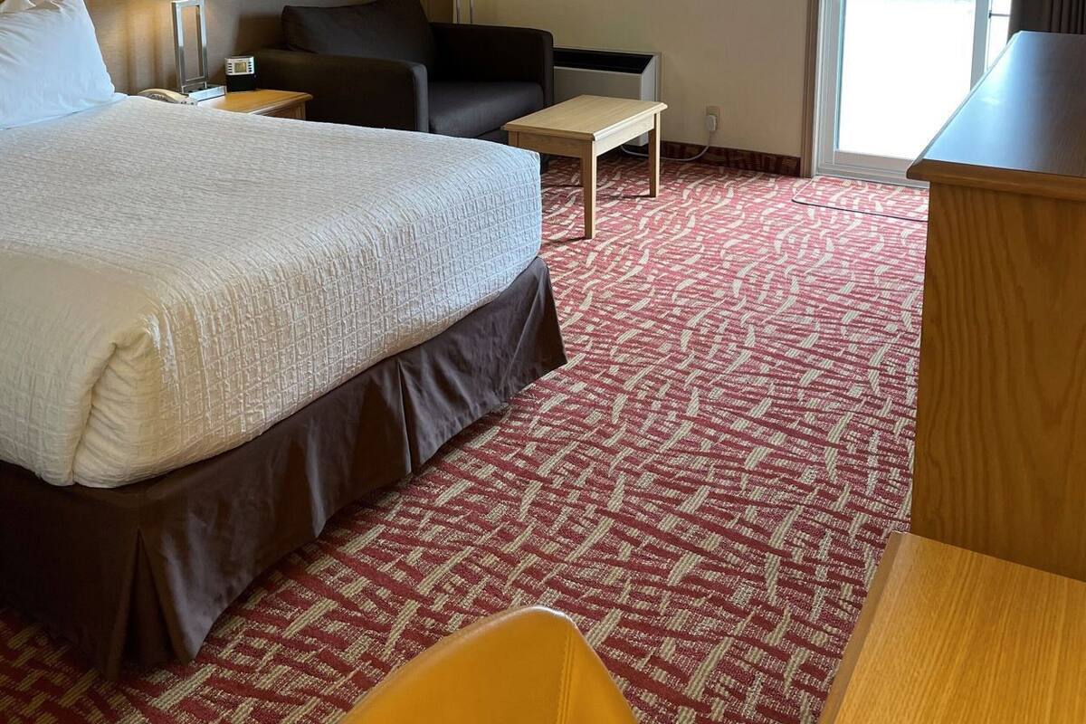 A hotel room with a bed, a desk, a chair, a sofa, and a window.