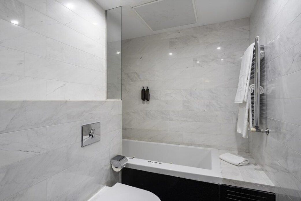 A modern bathroom with a bathtub, a toilet, and a shower area.