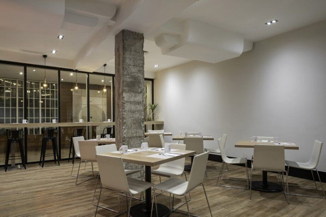 Un comedor moderno con mesas y sillas, un pilar grande y una partición de vidrio con vistas.