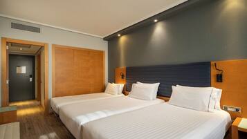 A hotel room with two beds, a wooden wardrobe, a door with a sign, and a wall-mounted light fixture.