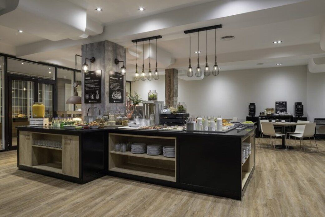 A modern kitchen with a central island, hanging pendant lights, and a dining area with chairs.