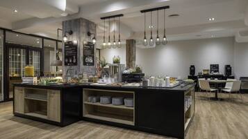 Una cocina moderna con una isla central, lámparas colgantes y una zona de comedor con sillas.