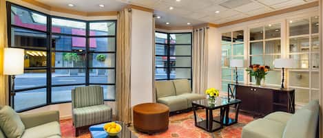A hotel lobby with a sofa, armchairs, a coffee table, and a decorative rug.