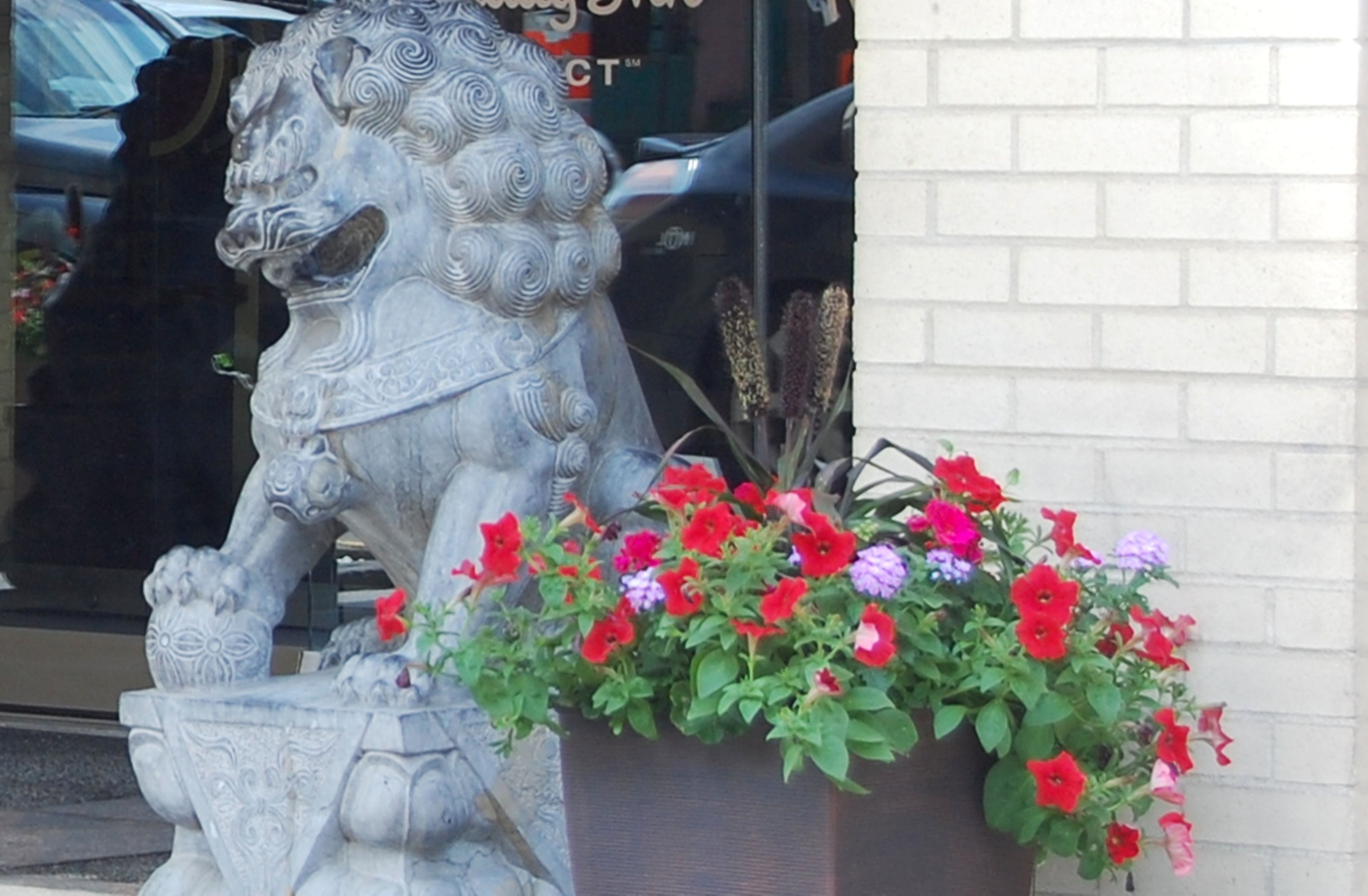 A stone lion statue in front of a building with a brick wall.