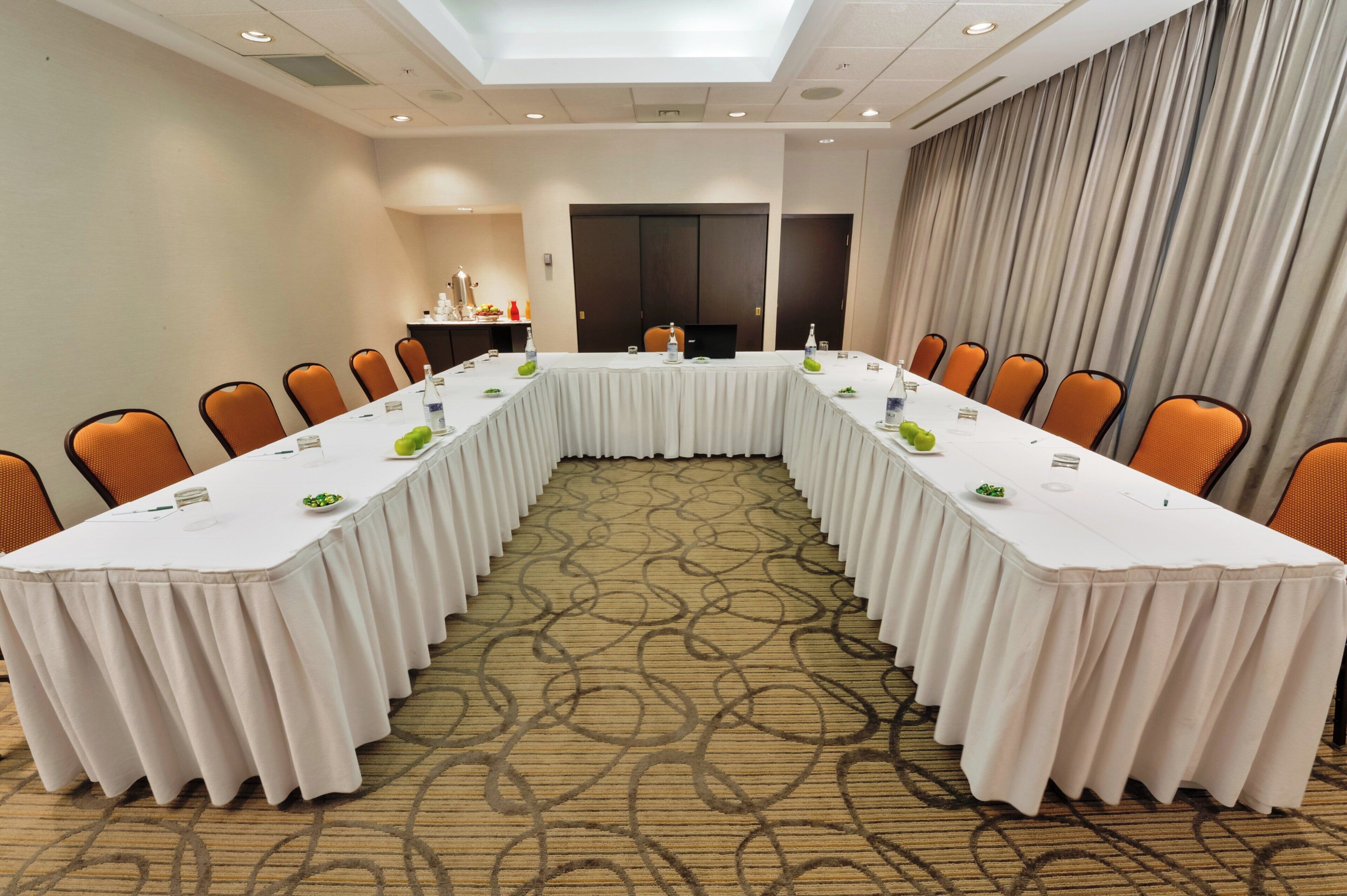 Una sala de conferències amb una taula llarga, cadires i un terra amb moqueta.