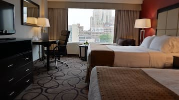 Une chambre d’hôtel équipée d’un lit, d’un bureau, d’une chaise, d’une télévision et offrant une vue sur la ville.
