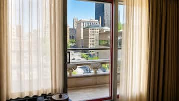 A room with a view of a cityscape through a glass door, featuring a balcony with a balustrade.