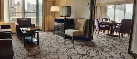 Ein Hotelzimmer mit Fernseher, Essbereich und Blick auf die Stadtlandschaft.