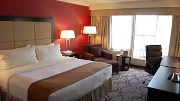 Una habitación de hotel con una cama grande, dos sillones, un escritorio y una mesita.