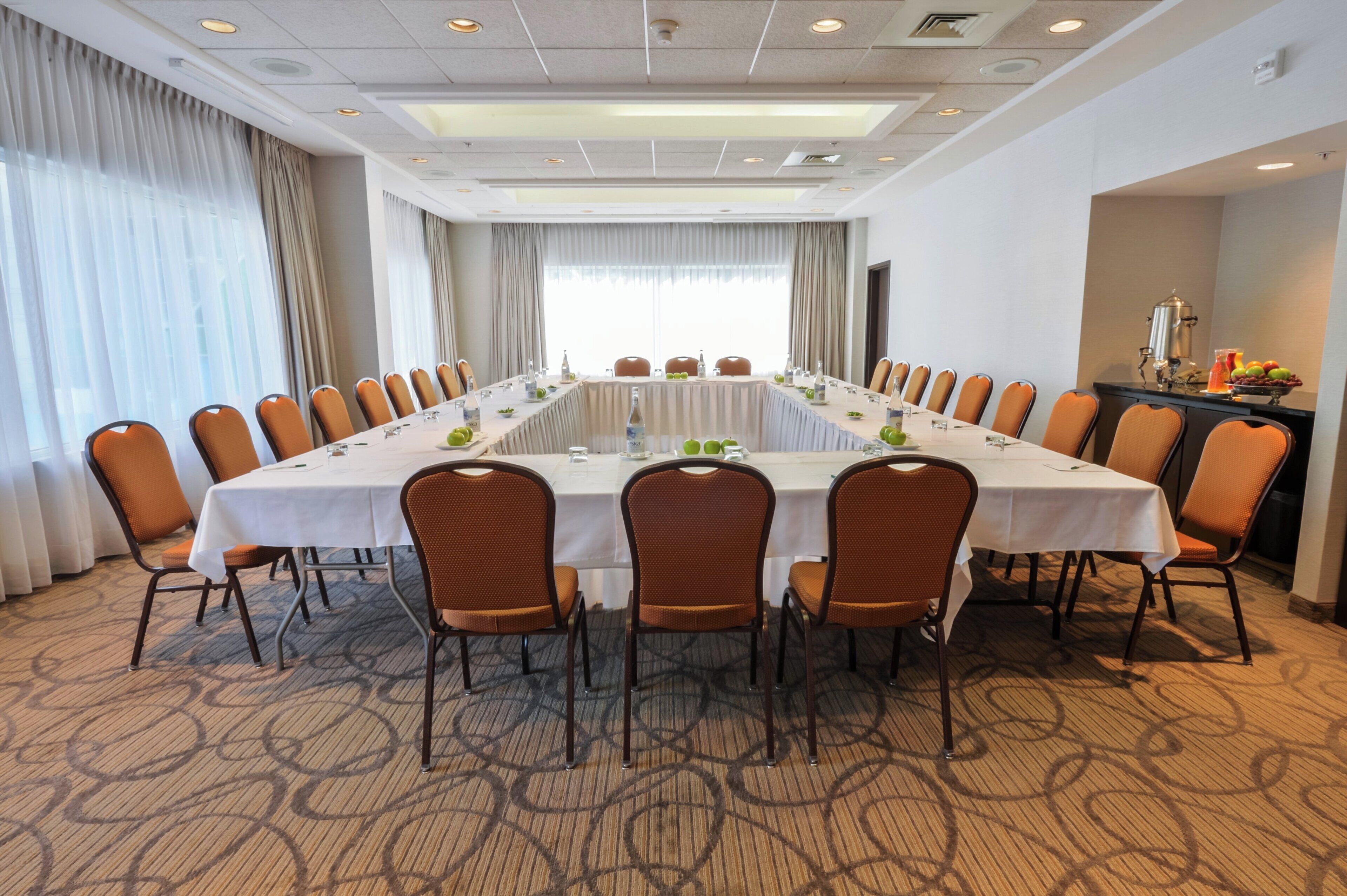 Sala de conferência com uma mesa comprida, cadeiras e um espaço para café.