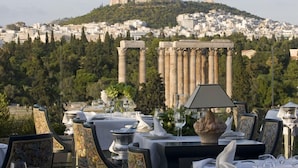 Mesa lista para comer con vistas a columnas griegas antiguas y una colina al fondo.