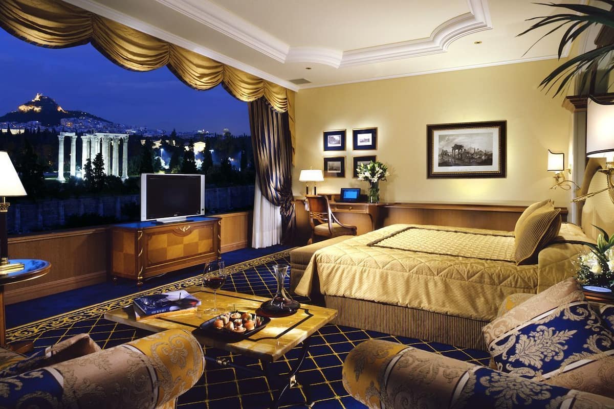Un'elegante camera d'hotel con un ampio letto, un divano, un tavolino da caffè e una TV.