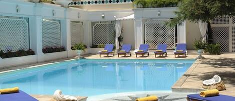 A pool area with lounge chairs and a tiled deck.