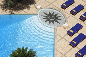 A swimming pool with a star-shaped sun design, lounge chairs, and a palm tree. - Royal Olympic Hotel (Athens)