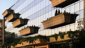 Un edificio moderno con ventanas de vidrio reflectante y balcones de madera con plantas.