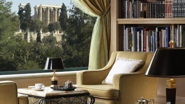 Una habitación con vistas a unas ruinas antiguas, una estantería, un sofá, una mesa de centro y una lámpara.