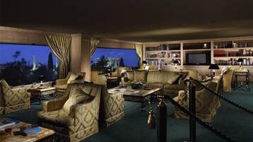 Un salón amplio con un ventanal grande, una estantería y un televisor.