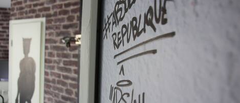 A wall with graffiti, a brick wall, and a door with a silhouette.