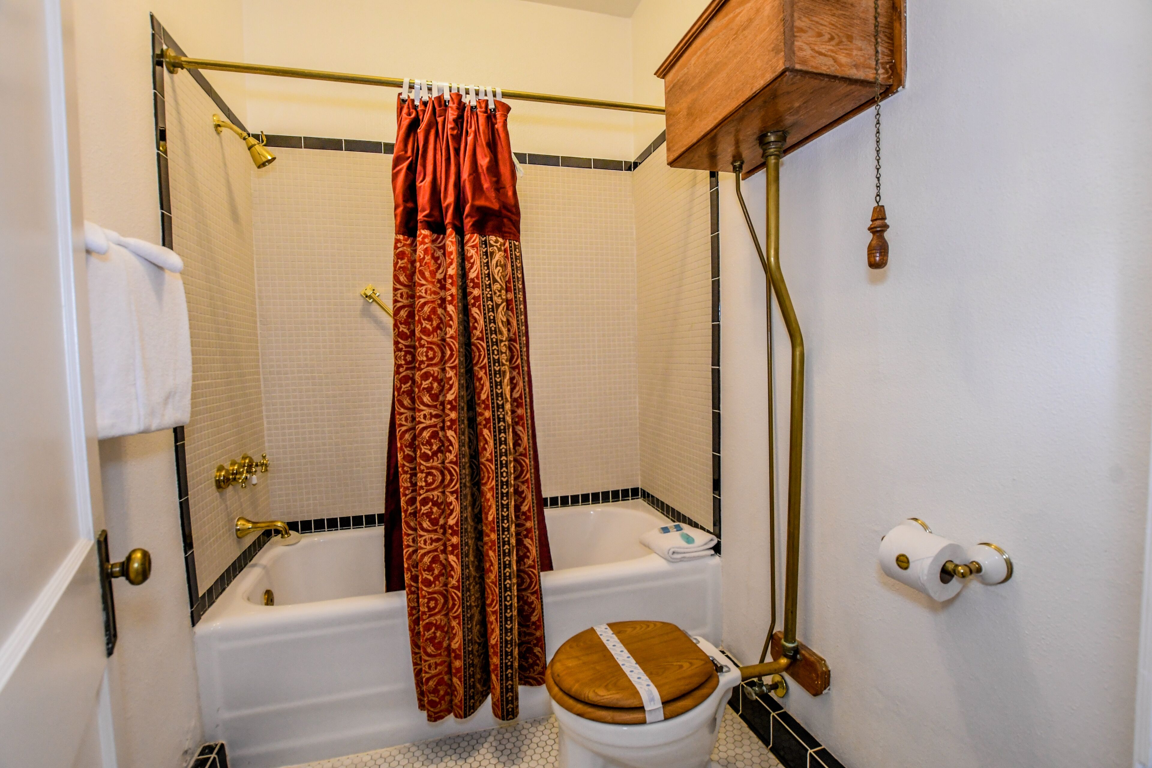 Une salle de bain avec une baignoire, des toilettes et un rideau de douche.